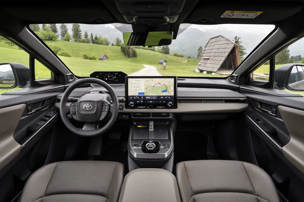 Intérieur moderne d'une Toyota avec tableau de bord numérique et vue panoramique extérieure.