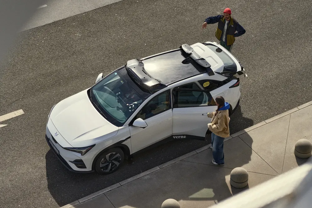 {"fr":"Voiture électrique blanche futuriste aux lignes modernes sur route, deux personnes à proximité.","nl":"Witte futuristische elektrische auto met moderne lijnen op de weg, twee personen in de buurt."}