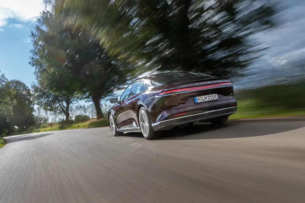 Voiture électrique Lucid Air roulant rapidement sur une route de campagne sinueuse.