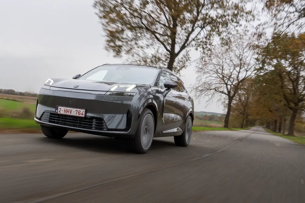 SUV électrique Seres 5 roulant sur une route de campagne bordée d'arbres.