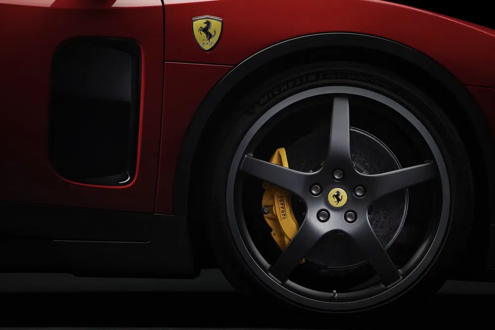 Roues et écusson Ferrari sur carrosserie rouge, étrier de frein jaune distinctif.