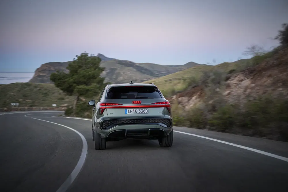 Audi Q3 rijdt op een kronkelige bergweg bij schemering.