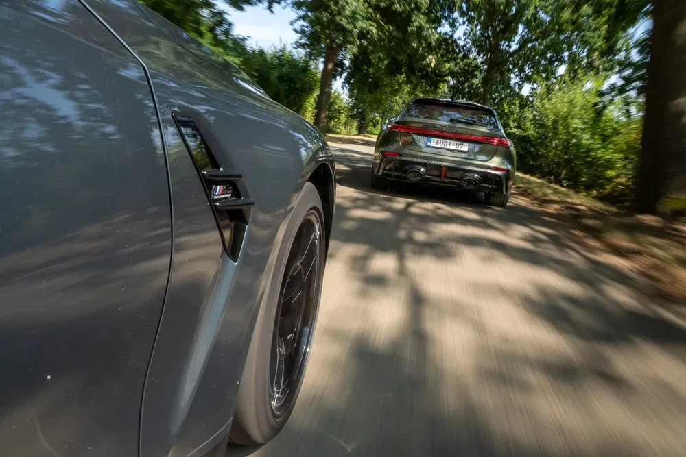 Dynamische race tussen BMW M en andere auto op boomrijke weg.