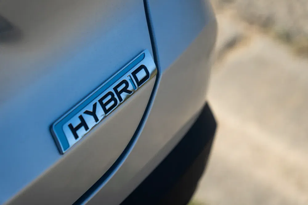 Badge métallique du mot 'Hybrid' sur la carrosserie d'une voiture argentée.
