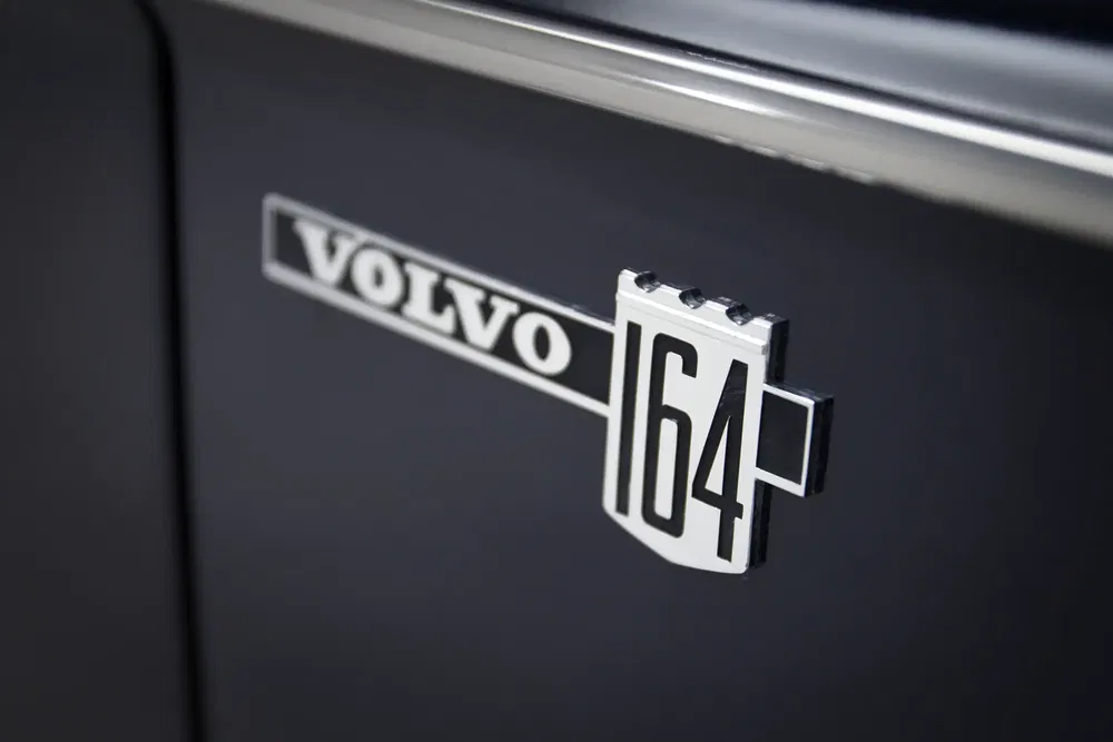 Embleem van Volvo 164 op zwarte carrosserie, benadrukt het klassieke retroontwerp.