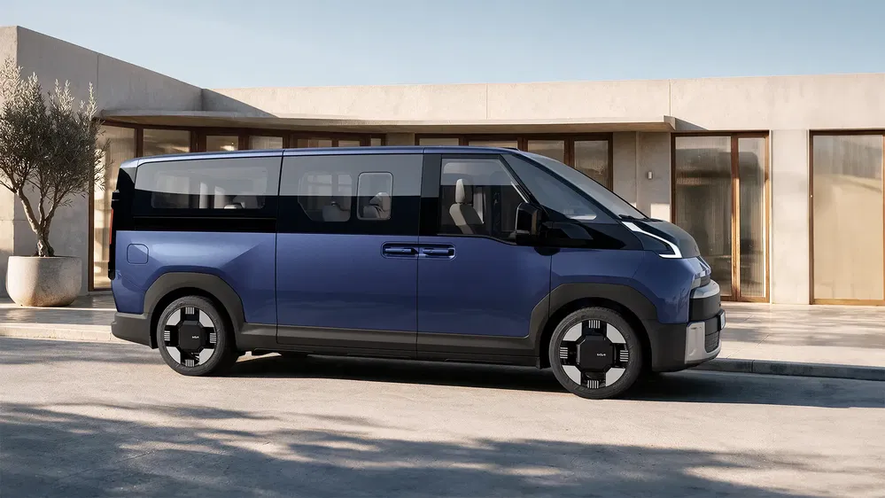 Hyundai Staria bleue garée devant une maison moderne par une journée ensoleillée.