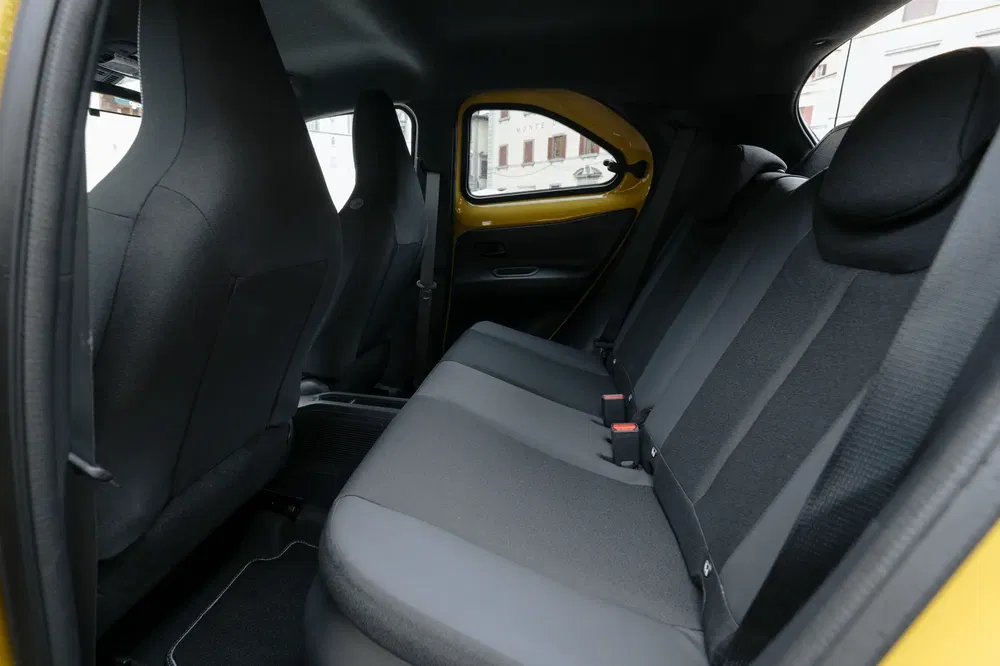 Intérieur arrière spacieux d'une Citroën Ami avec sièges en tissu noir.