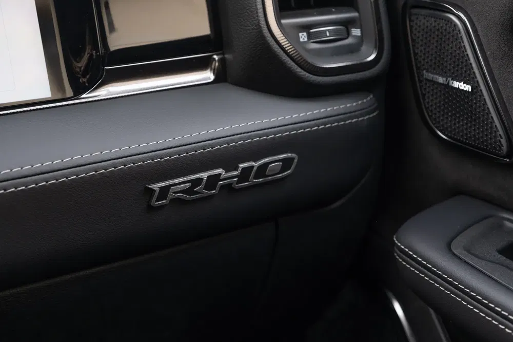 Interieur van RAM-auto met Harman Kardon-audiosysteem en RHO-logo op zwart leer.