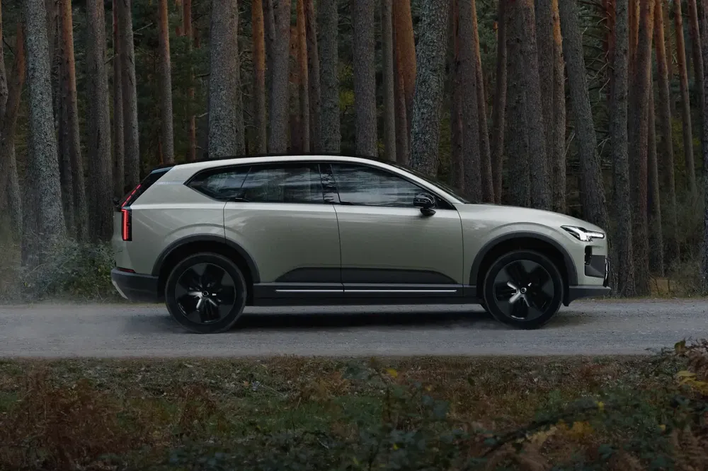 Volvo EX90 en forêt, SUV électrique moderne se déplaçant sur un chemin boisé.