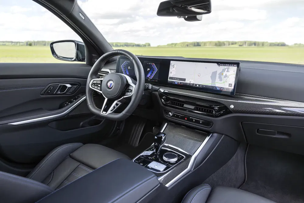 Intérieur d'une BMW moderne avec volant sport et écran tactile panoramique.