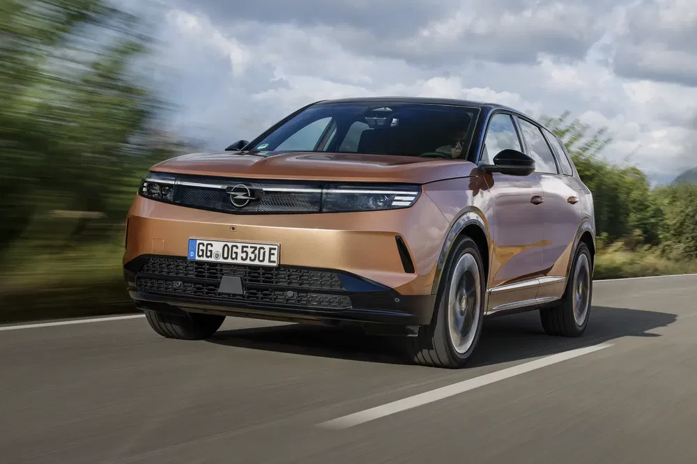 Bruine Opel SUV op weg, gekenmerkt door modern en aerodynamisch ontwerp.