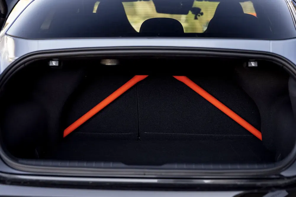 Coffre de voiture BMW M4 avec renforts orange sur fond noir.